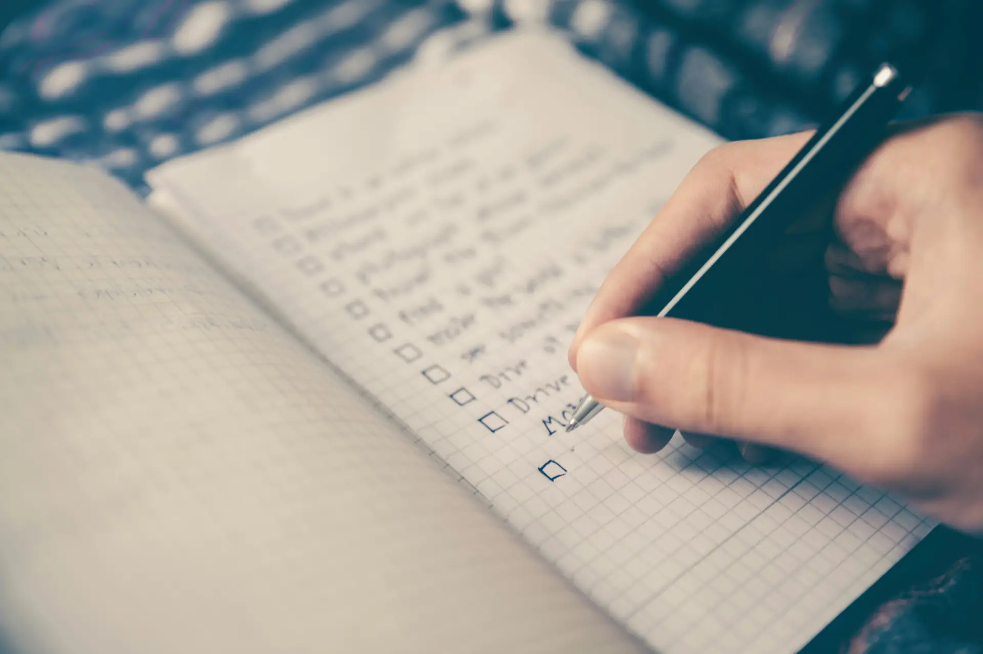Person writing a retreat planning checklist in a notebook