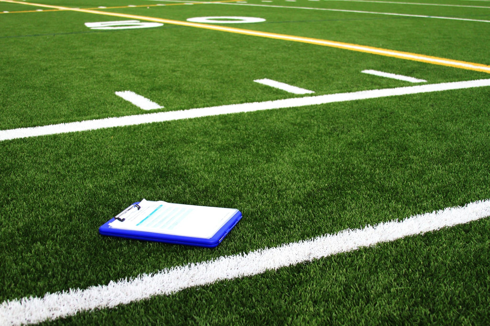 Retreat host playbook: Clipboard on a vibrant green football field. Planning strategies for calendar success. Retreat planning.